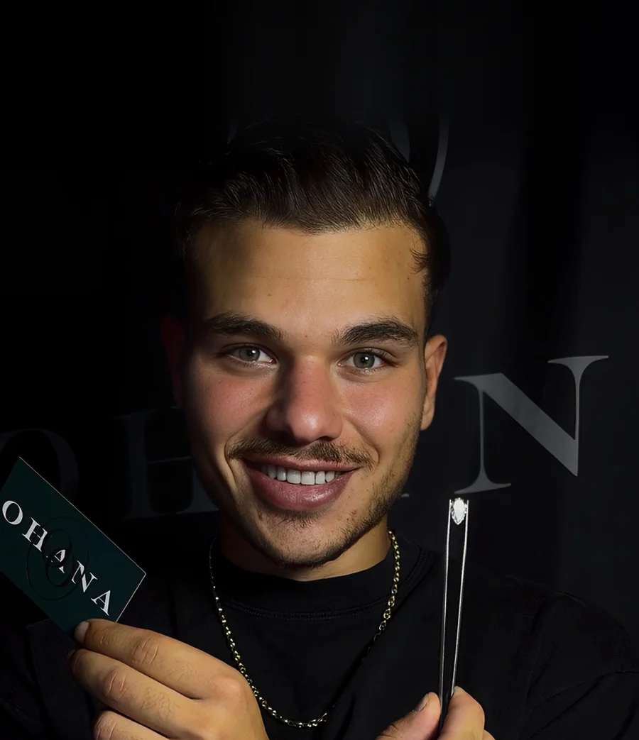 Ori Ohana, jewelry designer, holding an OHANA card and a diamond in tweezers